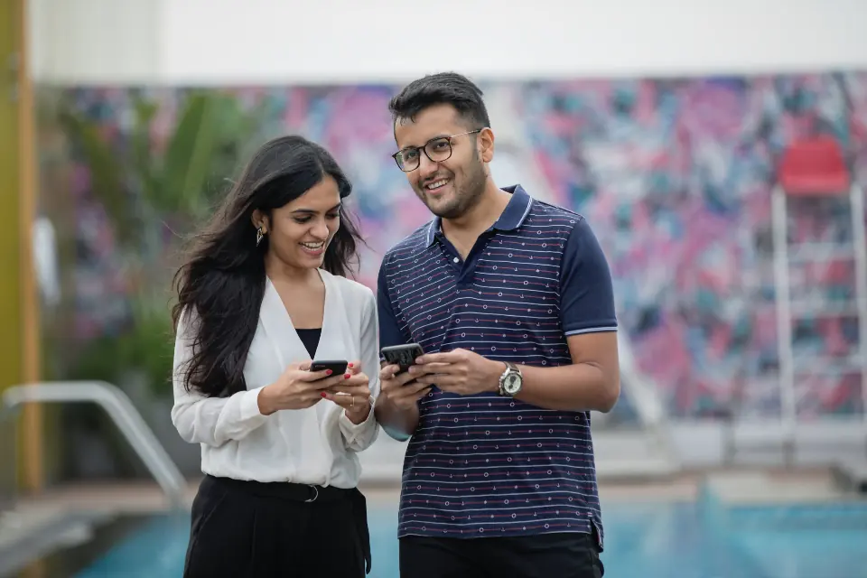 Dueños de un negocio sonriendo mientras revisan en el celular las ventas de su web