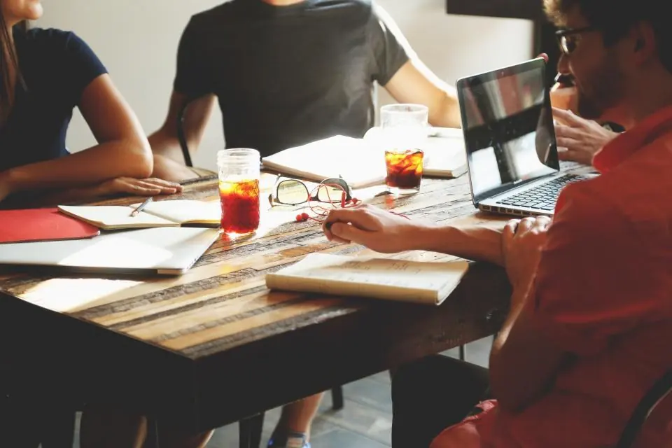 Equipo reunido alrededor de una mesa trabajando con portátiles